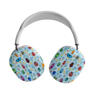May include: White over-ear headphones with earcups featuring a light blue background and a pattern of colorful insects and flowers. The insects include ladybugs, bees, and butterflies. The headband is white.