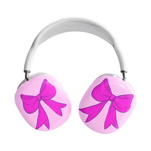 May include: White and silver headphones with pink earcups. Each earcup features a magenta bow design. The headband is white and the earcups are connected by silver metal. The headphones are set against a white background.
