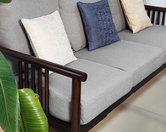 May include: A gray fabric sofa with dark wood arms and legs. The sofa has three cushions, two of which are white and one is blue.