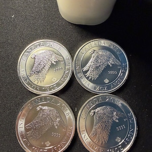 May include: Four silver Canadian coins from 2016, each with an eagle design. The coins are marked "Fine Silver 1 oz Argent Pur" and "9999". The coins are circular and have a reflective surface. The coins are approximately 3.8 cm in diameter.