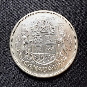 Puede incluir: Una moneda canadiense de 50 centavos de plata con el año 1958 y el escudo de armas de Canadá.