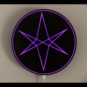 May include: A black circular wall decor with a purple six-pointed star in the center.