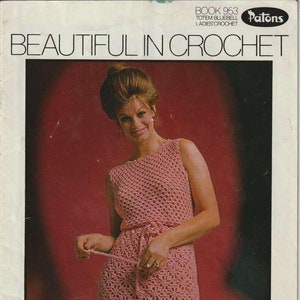 Könnte beinhalten: Ein Vintage-Häkelmusterbuch mit einer Frau in einem rosafarbenen Häkelkleid. Der Buchumschlag trägt den Titel "Beautiful in Crochet" und den Text "Book 953 Totem Bluebell Ladies' Crochet Patons 40c".