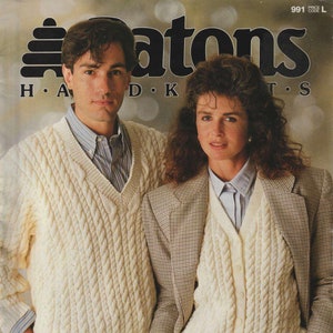 May include: Two people wearing white cable knit sweaters. The man is wearing a white sweater with a v-neck and the woman is wearing a white cardigan with buttons. The sweaters are described as being made of Totem 8 ply or Courtelle 8 ply.