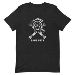 Könnte beinhalten: Schwarzes T-Shirt mit einer weißen Grafik eines Schäkels mit zwei gekreuzten Zurrgurten. Der Text "PRACTICE SAFE SETS" befindet sich unter der Grafik.