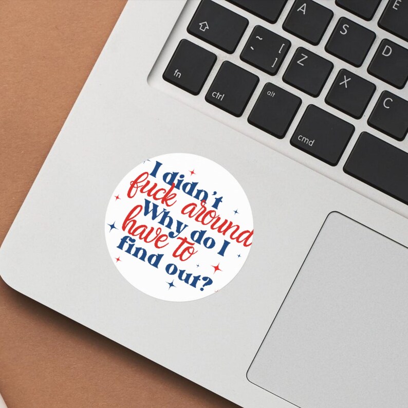 May include: A white round sticker with a blue and red text that reads "I didn't fuck around. Why do I have to find out?" with red stars around the text.