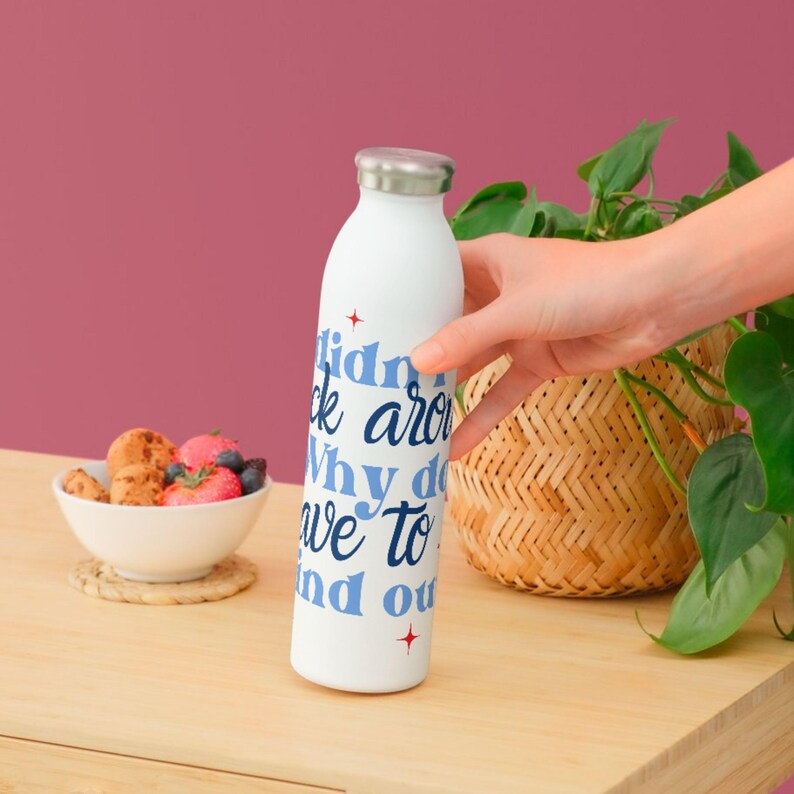 May include: White reusable water bottle with a blue and red design. The text on the bottle reads "I didn't ask around why do we have to find out".