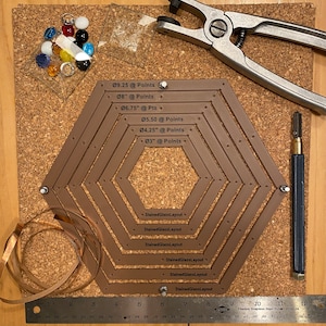 May include: A brown leather hexagon-shaped template with multiple circles marked with different sizes in inches and points. The template is surrounded by tools for stained glass work, including a copper strip, a ruler, a glass cutter, and a metal tool for setting glass.