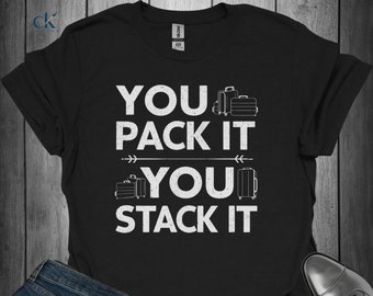 May include: Black t-shirt with white text that reads "You pack it, you stack it". The text is surrounded by images of suitcases.