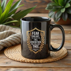 Może przedstawiać: Czarny ceramiczny kubek ze złotym i białym wzorem. Wz&oacute;r zawiera tekst "FEAR THOU NOT; FOR I AM WITH THEE... I WILL STRENGTHEN YEA, I WILL HELP THEE," oraz odniesienie "ISAIAH 41:10 - (KJV)".