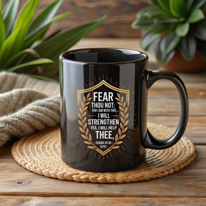 Może przedstawiać: Czarny ceramiczny kubek ze złotym i białym wzorem. Wz&oacute;r zawiera tekst "FEAR THOU NOT; FOR I AM WITH THEE... I WILL STRENGTHEN YEA, I WILL HELP THEE," oraz odniesienie "ISAIAH 41:10 - (KJV)".