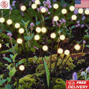 May include: A collection of outdoor garden lights featuring thin black metal stems topped with small, glowing warm white spherical bulbs. These decorative lights are arranged in a cluster, mimicking the appearance of fireflies in a garden.