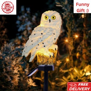 May include: A white owl-shaped solar garden light with black spots and yellow eyes. The light is perched on a brown tree stump and has a black stand. The text "Funny Gift :)" is visible. The image also includes the text "Best Seller".