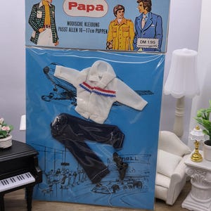 May include: Vintage doll clothing set, packaged in a blue box with the word "Papa" in red. The set includes a white jacket with red and blue stripes, dark blue pants, and black shoes. The box features illustrations of men in various outfits.