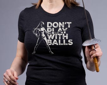 May include: A black t-shirt with a white graphic of a woman fencing with the text "DON'T PLAY WITH BALLS".