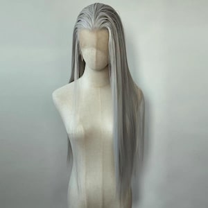 Puede incluir: Una peluca larga, recta, gris plateada con un frente de encaje. La peluca está peinada con raya en medio y cae recta por la espalda.