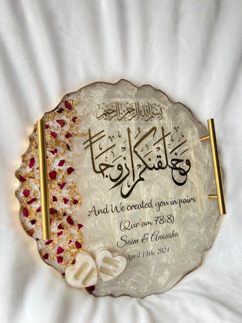 May include: A decorative resin tray with gold handles and edges. The tray features gold calligraphy and the English text "And We created you in pairs." It is decorated with red rose petals and two heart-shaped embellishments. The date April 13th, 2024 is also included.