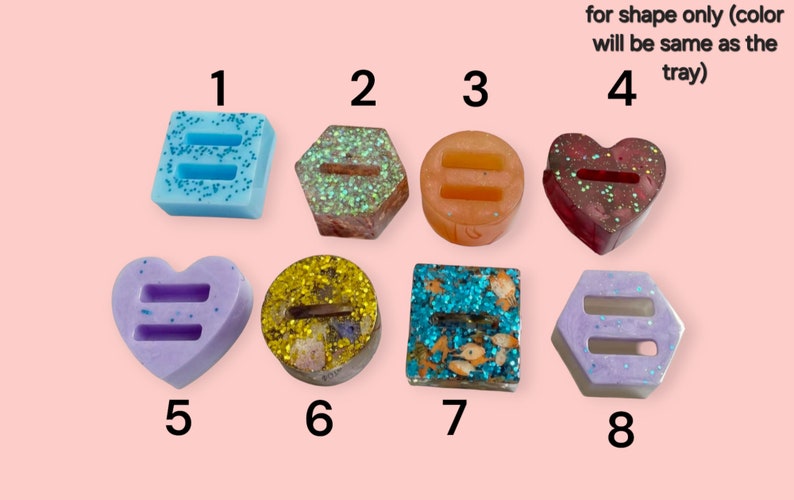 May include: A collection of eight decorative resin pieces in various shapes, including squares, hexagons, circles, and hearts. Each piece features a double-bar symbol and is filled with glitter or small decorative elements. The text "for shape only (color will be same as the tray)" is visible.