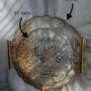 May include: Decorative resin tray set, featuring a 10-inch and a 13-inch tray. The trays have a white and gold design with gold handles. The trays have Arabic calligraphy and the text "And We created you in pairs" (Qur'an 78:8), along with names and a date.