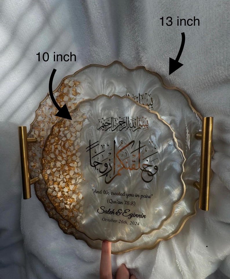 May include: Decorative resin tray set, featuring a 10-inch and a 13-inch tray. The trays have a white and gold design with gold handles. The trays have Arabic calligraphy and the text "And We created you in pairs" (Qur'an 78:8), along with names and a date.