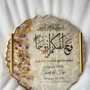 May include: A decorative resin tray with gold trim and handles. The tray features gold leaf and purple accents on the left side. The tray has Arabic calligraphy and English text that reads "And We created you in pairs" and wedding details.
