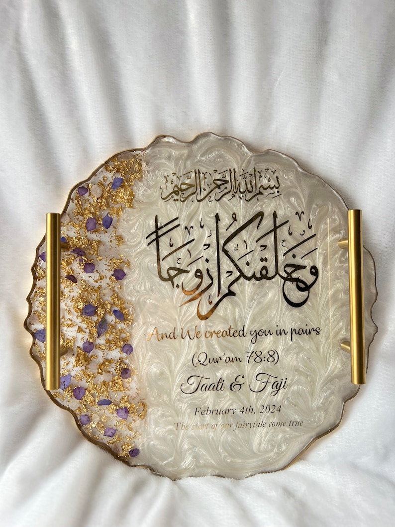 May include: A decorative resin tray with gold trim and handles. The tray features gold leaf and purple accents on the left side. The tray has Arabic calligraphy and English text that reads "And We created you in pairs" and wedding details.