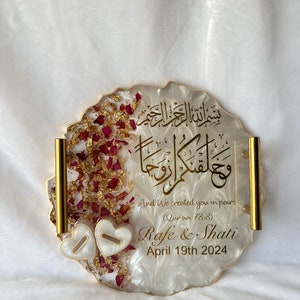 May include: A decorative, resin tray with gold trim and handles. The tray features gold script, dried rose petals, and two heart-shaped accents. The text includes names and a date.