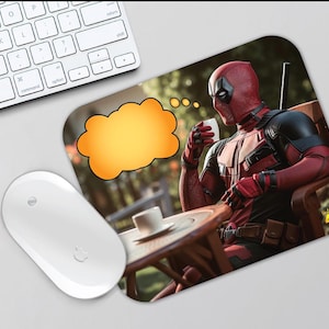 May include: A red and black Deadpool character sitting at a table with a cup of coffee. A thought bubble above his head is yellow. The background is a blurred image of a garden.