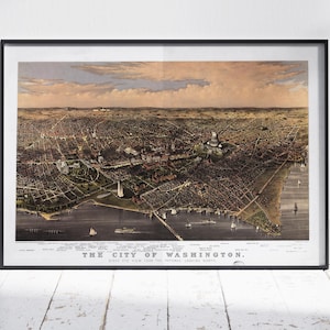 Puede incluir: Impresión enmarcada de un mapa antiguo de Washington, D.C., en un marco negro. El mapa muestra una vista aérea detallada de la ciudad, con el título "THE CITY OF WASHINGTON" en la parte inferior. La impresión se muestra contra una pared blanca y un suelo de madera.