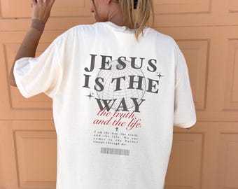 May include: A white t-shirt with a graphic print of a globe with the text "JESUS IS THE WAY the truth, and the life."  The text below the globe reads "I am the way, the truth, and the life. No one comes to the Father except through me."