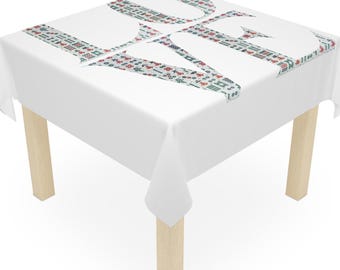 May include: A white tablecloth featuring the word "LOVE" in a pattern of small, colourful shapes. The cloth covers a small, square table with light-coloured wooden legs. The table is a square shape.