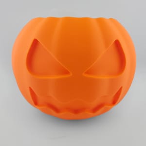 以下が含まれることがあります： オレンジ色の3Dプリントされたカボチャ型の容器で、彫刻された目と口があります。ハロウィーンをテーマにしたこの容器は丸く、上部が開いています。カボチャは質感のある表面を持ち、お菓子を入れたり、装飾品として使用するのに適しています。