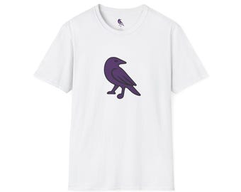 May include: White t-shirt featuring a purple cartoon raven graphic on the front. The shirt has a crew neck and short sleeves. A small raven logo is on the upper back of the shirt. The design is simple and modern.