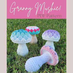 May include: Four crocheted mushroom amigurumi toys in different colors, including blue, pink, purple, and white. The mushrooms are sitting on a bed of green grass. The text "Granny Mushie! PDF Pattern" is displayed on a pink background.
