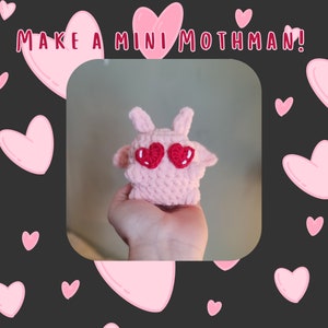 May include: A pink crocheted plush toy shaped like a moth with red heart-shaped eyes. The toy is being held in a person's hand. The background is black with pink hearts.