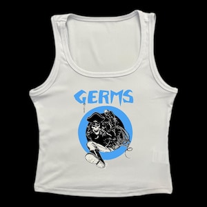 May include: White ribbed tank top with a blue circle graphic of a skeleton wearing a pirate hat and holding a microphone. The text "GERMS" is printed above the graphic.