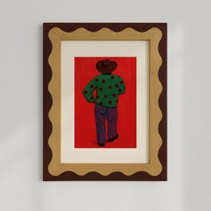 Puede incluir: Una ilustración enmarcada de una persona que lleva un suéter verde con estrellas rojas y pantalones a rayas azules y rojas. La persona lleva un sombrero marrón y está de espaldas al espectador contra un fondo rojo.