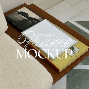 Puede incluir: Una maqueta de marco de imagen plateado sobre una pila de libros en una mesa de madera. El marco está en blanco y listo para su diseño.