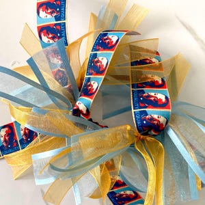 May include: Blue and gold ribbon with a repeating pattern of a man's face and the words "Equality" and "Equal".