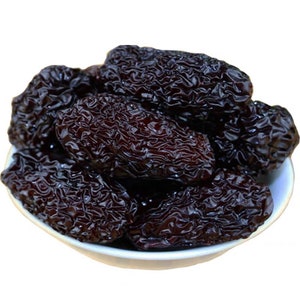 May include: A bowl of dried black dates, a popular ingredient in Asian cuisine and traditional medicine.