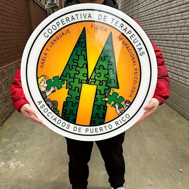 May include: A circular sign with a white border and Spanish text. The centre has a yellow background with two green puzzle-piece arrows and the text "ASOCIADOS DE PUERTO RICO". Cartoon figures hold puzzle pieces.