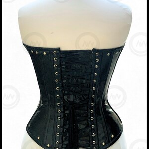 May include: Black corset with a matching choker. The corset features a glossy finish, metal eyelets, and a lace-up back. The choker has a buckle closure. The corset is displayed on a mannequin.