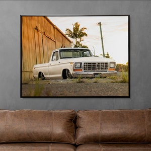 May include: A white vintage pickup truck parked in front of a wooden building with a palm tree in the background.