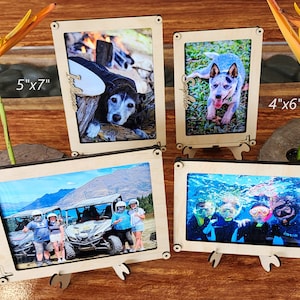 以下が含まれることがあります： 異なる写真が4枚入った木製の写真フレーム。フレームは12.7cm x 17.8cmと10.2cm x 15.2cmで、背面にスタンドが付いています。写真は、犬、ATVに乗った人々、シュノーケリングをしている人々、犬です。