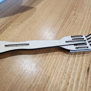 K&ouml;nnte beinhalten: Eine Holzgabel mit einem langen Stiel und f&uuml;nf Zinken. Die Gabel ist aus hellbraunem Holz und hat eine nat&uuml;rliche Oberfl&auml;che.