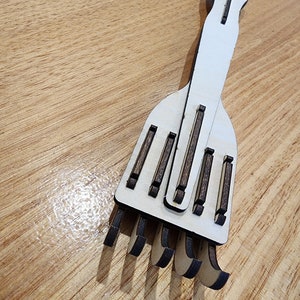 K&ouml;nnte beinhalten: Ein h&ouml;lzerner Handrechen mit einem wei&szlig;en Stiel und braunen Holz-Zinken. Der Rechen ist f&uuml;r den Einsatz im Garten oder f&uuml;r andere Aufgaben konzipiert.