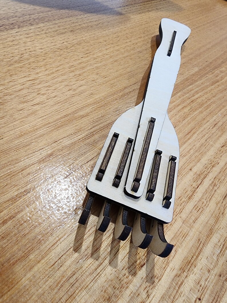 K&ouml;nnte beinhalten: Ein h&ouml;lzerner Handrechen mit einem wei&szlig;en Stiel und braunen Holz-Zinken. Der Rechen ist f&uuml;r den Einsatz im Garten oder f&uuml;r andere Aufgaben konzipiert.