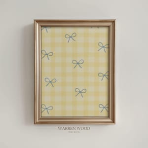 May include: A framed print featuring a yellow and white gingham pattern with light blue bow illustrations. The frame is gold-toned. The text "WARREN WOOD PRINTS" is at the bottom of the print.