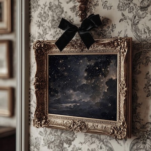 May include: An ornate, gold-framed painting depicting a night sky filled with stars and clouds. A black velvet bow is tied above the frame. The painting is displayed against a floral wallpaper.