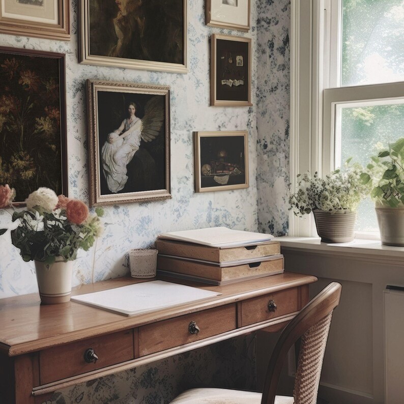 May include: A vintage-style home office with a wooden desk, drawers, and a chair. The wall is adorned with framed artwork and floral wallpaper. A window with potted plants provides natural light, creating a cozy and artistic workspace.